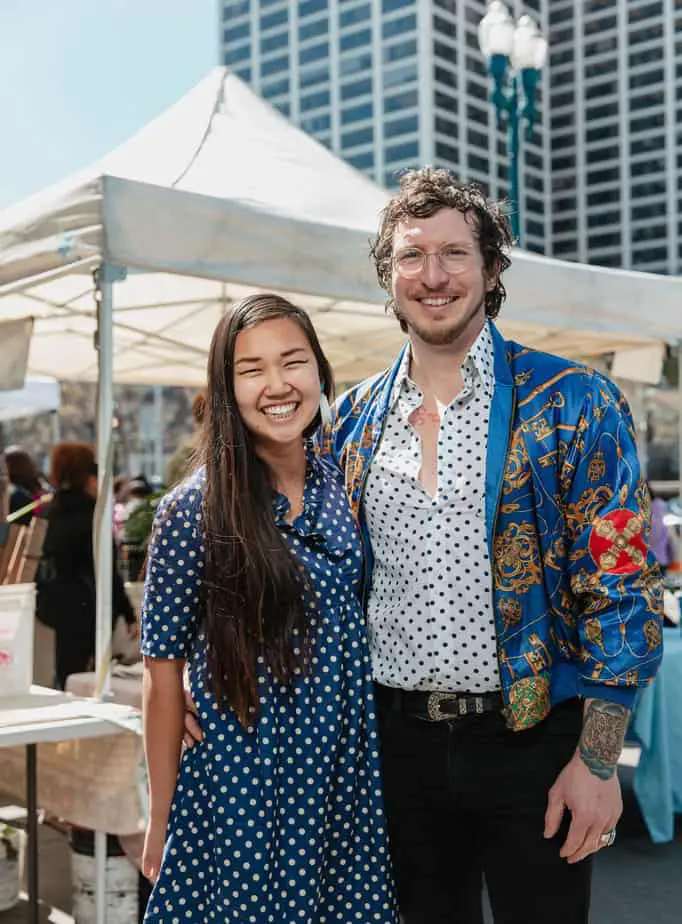 Kayla Abe and David Murphy in front of various tents at the Ferry Building Farmers Market.
